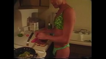 Tanned gay in lingerie prepares dinner in the kitchen while his friend fucks him in the ass