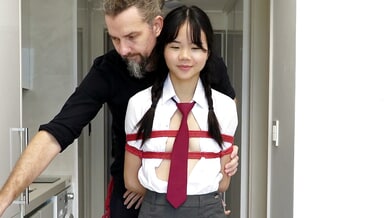 Young Japanese student in school uniform tied up and suspended in a narrow hallway