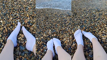 Playing with my feet in white socks with pebbles on the beach