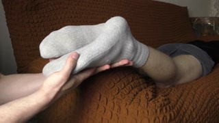 a guy makes a foot massage to a guy in socks - ARTEM SUCHKOV