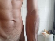 Muscular boy contracts muscles and penis in bathroom