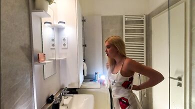 Blonde beauty in pink satin nightie teases herself in the bathroom before bed