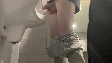 2 boys in sneakers having fun at public toilets' urinal