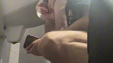 2 boys in sneakers having fun at public toilets' urinal