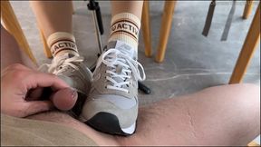 Teasing under the table with her New Balance sneakers