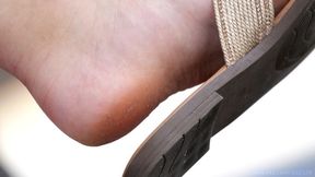 Dirty feet slippers dangling, foot fetish admiration, feet and shoes close-up.