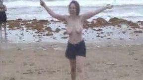 Playful chick gets nude on the beach and flashes her big boobs