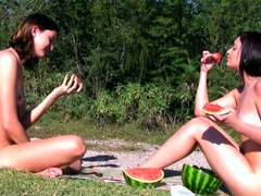 Naked teens enjoying the sun and eating watermelon outdoors