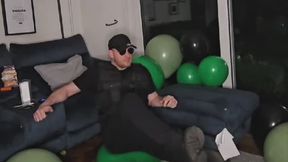 Military Tom Destroys and army of green and black balloons by hand, sit and foot pops