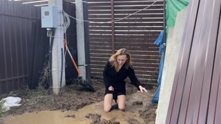 A fashionista in high-heeled boots climbed into a huge dirty pit with mud and water