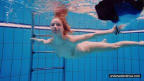 ”Ginger sexy girl swimming naked in the pool”