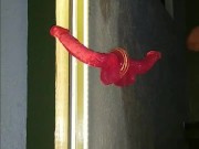 Sissy in chastity fucks her ass with red dildo in front of the mirror.