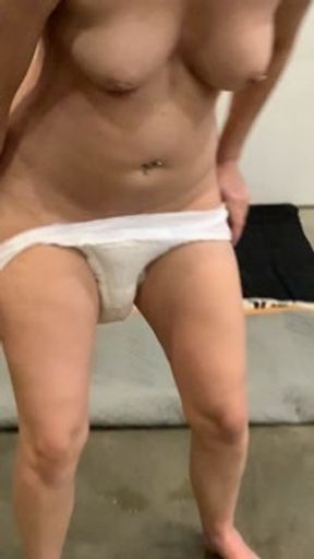 Girl pees in diaper while sitting on floor til it leaks out
