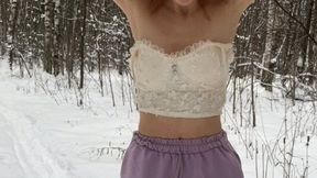 A girl in a terrible frost stands in the forest in ballet flats, shorts and a top and shakes from the cold