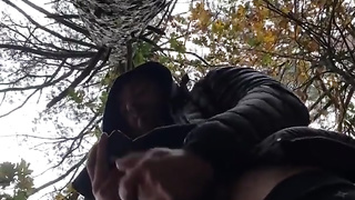 Bulky bodybuilder is milking off in woods outdoor public place