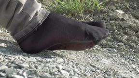 Jeans feet in black nylon socks on the seashore