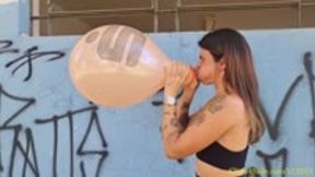 Maya Blows to Pop Two Printed Balloons