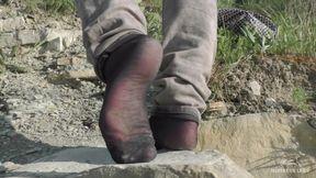 Jeans feet in black nylon socks on the seashore
