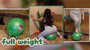 Mistress Mersiiik, wearing sexy gray leggings and a bra, bounces on a large green fitness ball, squashes it, and steps on it with her bare feet. inflatable fitness ball leggings butt bare feet jumping foot fetish