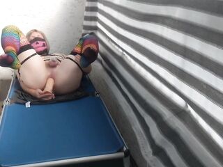 Caged sissy plays with her sex toy on public balcony