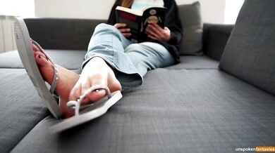 POV foot fetish scene with bare soles in focus while someone reads on the couch