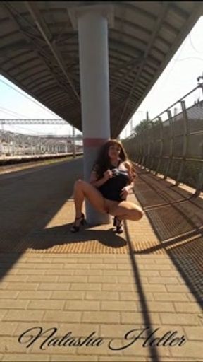 A beautiful, young exhibitionist girl in a transparent dress shows her pussy at the railway station.