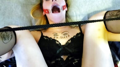 Tattooed submissive in black lace lingerie takes a deep throat with ball gag