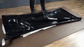 Face down flogging in a black latex bed