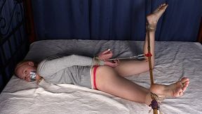 Barefoot tapegagged Mary in grey long-sleeve and red thongs, hogtied with her feet wide-spread and tied to bamboo stick, wiggles on the bed (HD WMV)