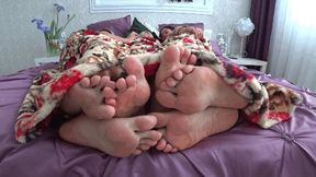 Three pairs of legs flirting under the blanket aS