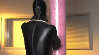 Spandex zentai babe with fishing line tied to concrete post