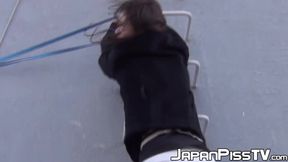 Young Asian cutie outdoors tied up and pees from the ladders