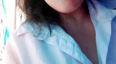 Young woman in white blouse films herself touching her Brazilian waxed pussy by the apartment window
