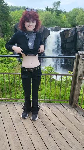 Girl in black and white shirt posing at waterfall
