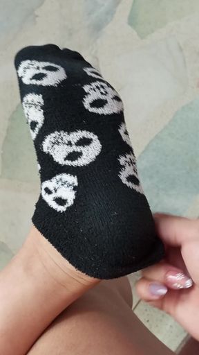 Slowly peeling off socks to show bare feet and wiggling toes