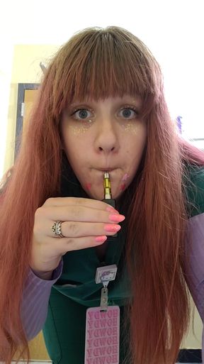 Woman with red hair and pink nails holding a vape pen