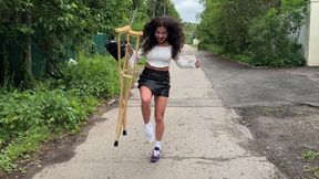 Girl on crutches, walking on crutches, broken leg, pulled ligaments, cast on leg, girl walking down the street on crutches and sneakers