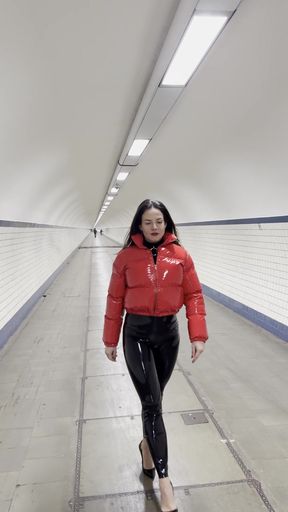 Woman in red jacket walking through subway tunnel