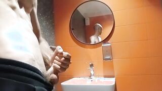 A bony boy with a clean-shaven head faps off in a shopping mall restroom