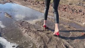 A girl in very high-heeled shoes walks through very sticky mud that clings to all her feet and shoes (short version)