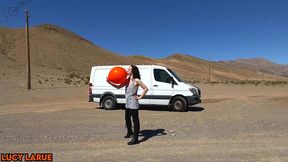 vanlifer blows up a giant orange balloon in the desert