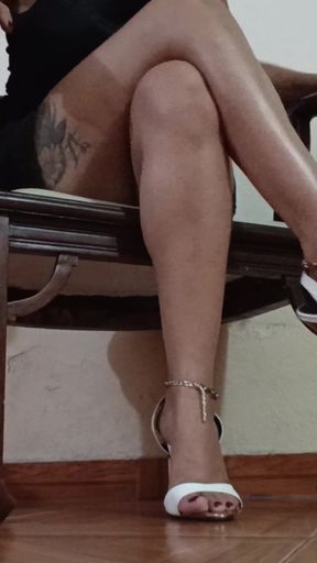 Her Long Legs Are Crossed, and Her High Heels Dangle From Her Feet as She Sips a Delicious Cup of Coffee