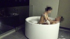 Asian couple tangled in outdoor tub &mdash;  someone watches from the edge
