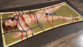 Bondage with ropes to the frame in latex bed with vibro