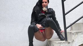 Elegant and wicked brunette in leather jacket urinates on the stairs