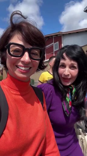 Woman in orange sweater and glasses with another woman