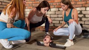 three girls spitting on a slave captive in dirty basement