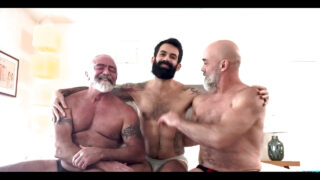 Dövmeli ayı baba, amatör bir üçlüde devasa bir penis tarafından çıplak bir şekilde arkadan sertçe beceriliyor; bu üçlüde oral seks ve anal seks de yer alıyor.