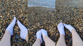 playing with my feet in white socks with pebbles on the beach