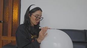 Marianna blows a white balloon full of red kisses to make it pop